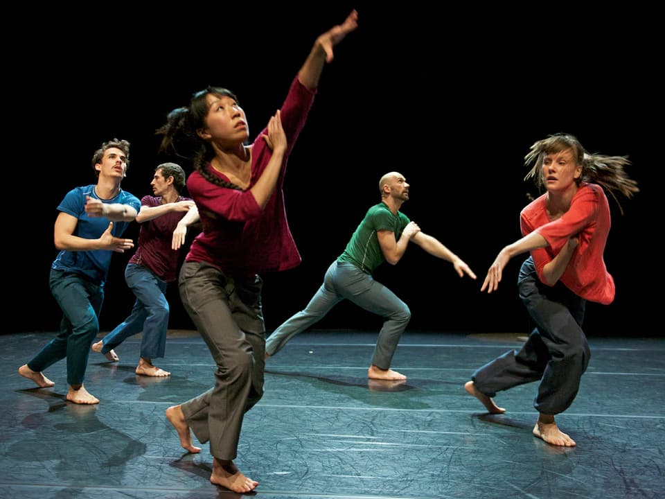 Fünf Tänzerinnen und Tänzer in farbigen Shirts bewegen sich über die Bühne.