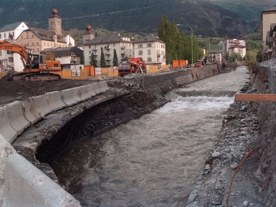 Ein Fluss, am Ufer stehen Bagger und weitere Baumaschinen.