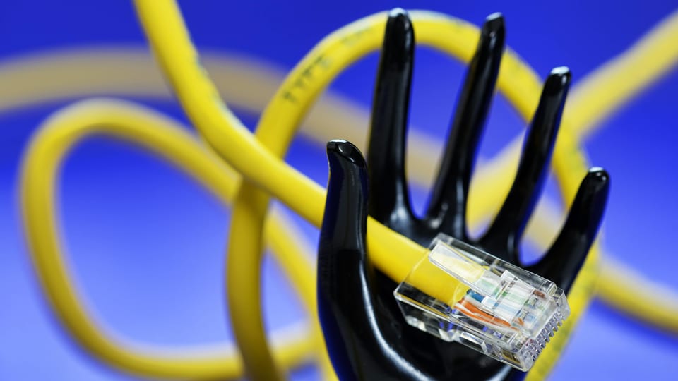 Eine Plastikhand hält ein LAN-Kabel.