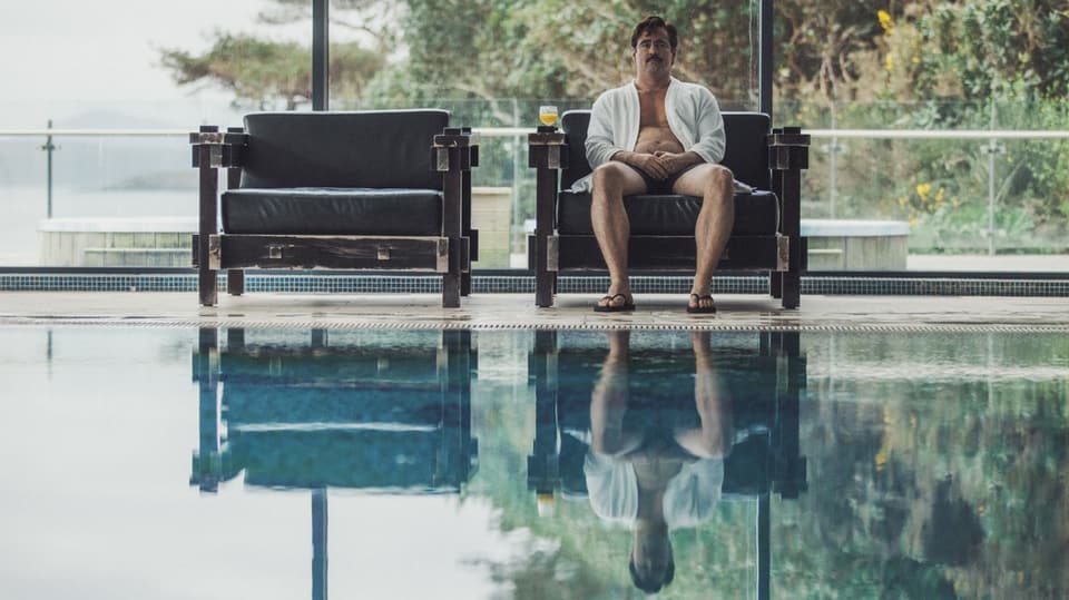 Mann in Bademantel und Flipflops sitzt auf einem von zweien Designersesseln an einem Pool