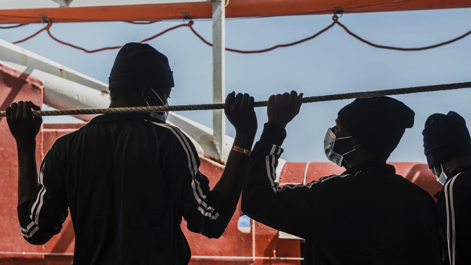 Zwei afrikanische Männer von hinten auf einem Schiff.