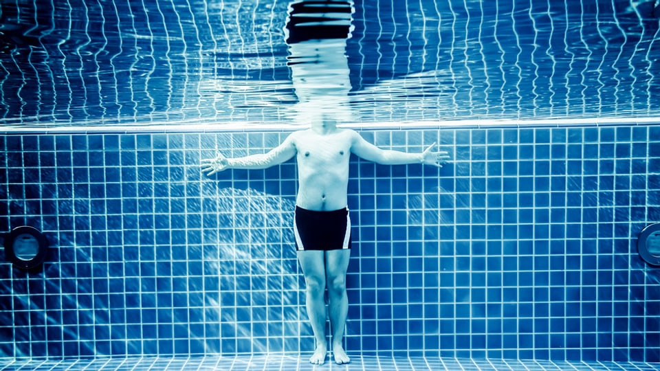 Eine Person steht in einem Schwimmbad. 