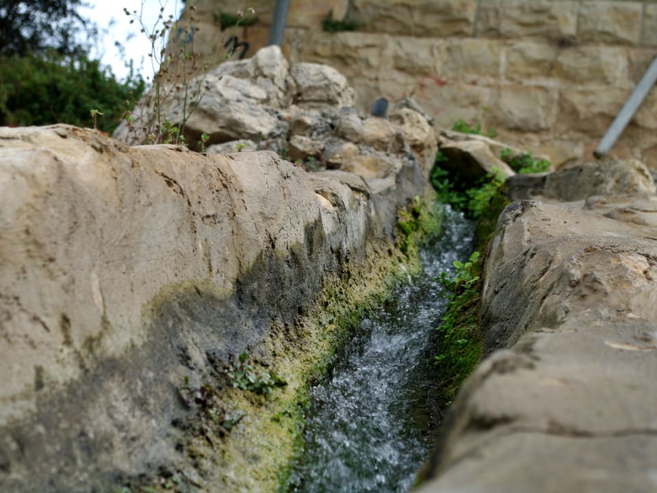 Blick auf einen Kanal aus Stein, in dem Wasser fliesst.
