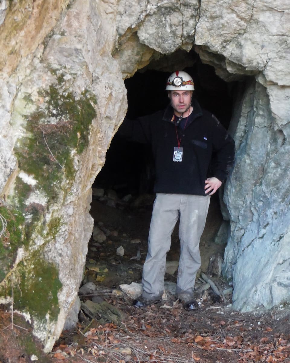 Mann mit Helm steht im Höhleneingang.