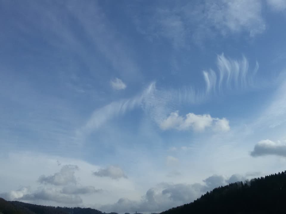 Verschiedene Wolken in unterschiedlichen Höhen über dem Züricher Unterland, die Sonne scheint.