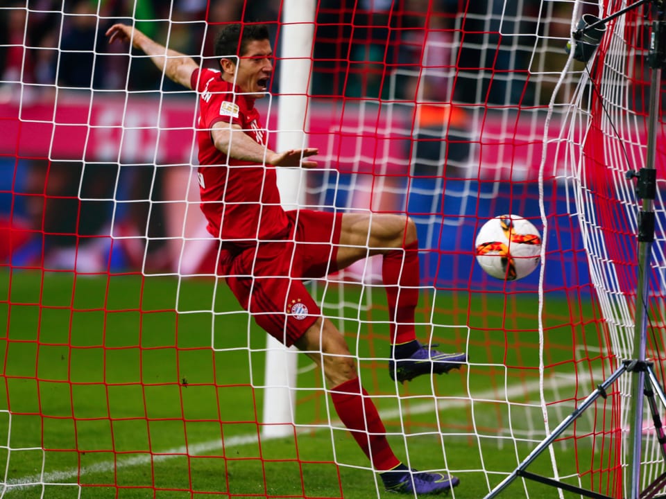 Robert Lewandowski von Bayern München schiesst den Ball ins Netz.