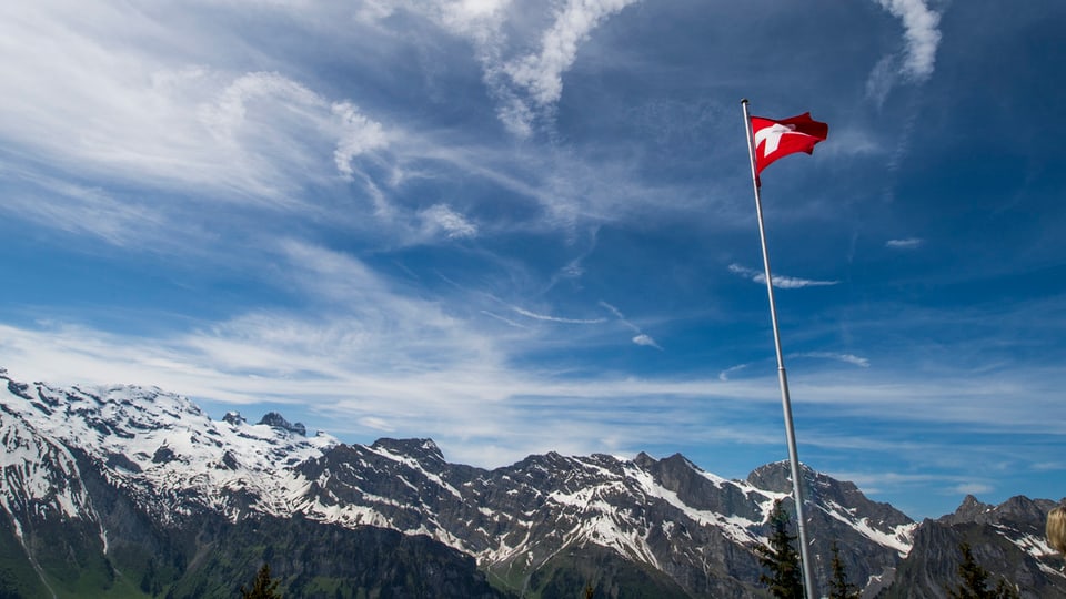 Eine Schweizer Flagge in den Alpen im Wind.