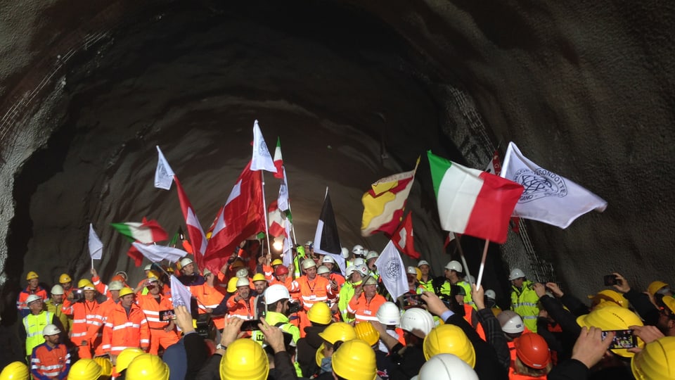 Bauarbeiter in einem Tunnel: Sie schwenken verschiedene Flaggen.
