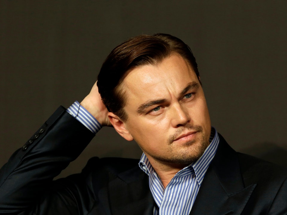 Schauspieler Leonardo DiCaprio stützt mit einer Hand seinen Kopf.