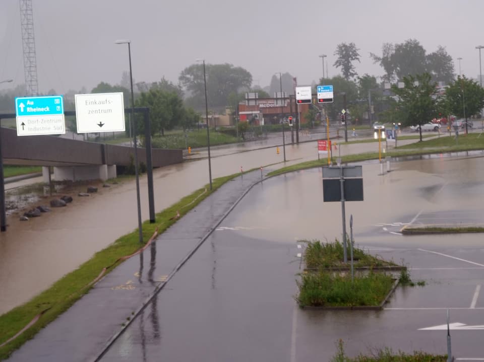 Strasse und Parkplatz stehen unter Wasser