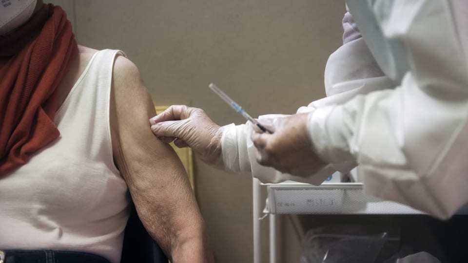 Vor der Impfung: Die ärztliche Fachperson desinfiziert die entblösste Schulter einer Impfwilligen.
