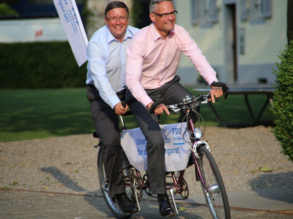 FDP- Regierungsräte Urs Hürlimann und Matthias Michel zu zweit auf einem Tandem. 