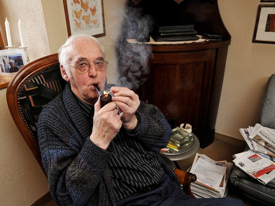 Helmut Hubacher, auf einem Stuhl sitzend und Pfeife rauchend.