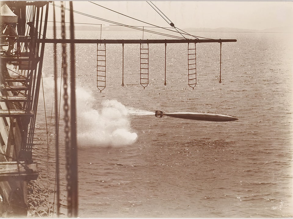 Man sieht den Abschuss eines Torpedos um 1900, der knapp über der Meeresoberfläche geschieht.