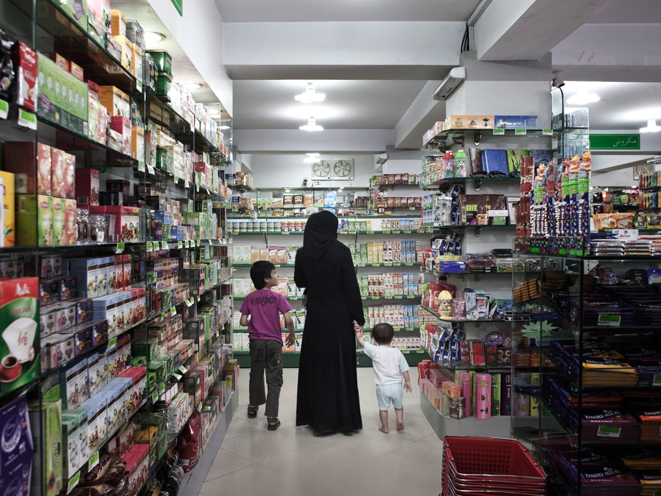 Eine Frau in einer Burka läuft mit zwei Kindern durch einen Supermarkt.