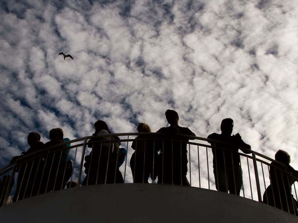 Eine Gruppe von Menschen steht am Geländer eines Aussichtspunkts.