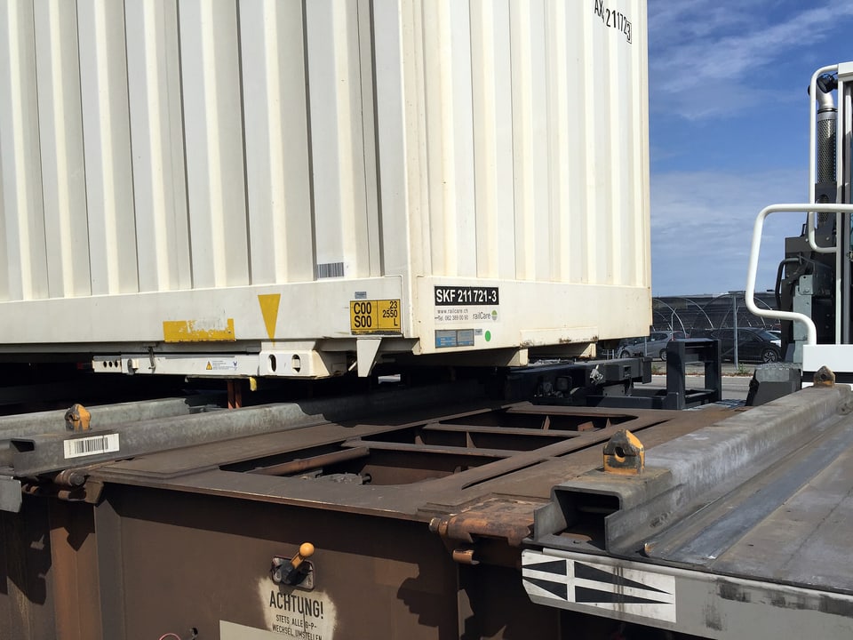 Container wird seitwärts auf Bahnwagen verladen