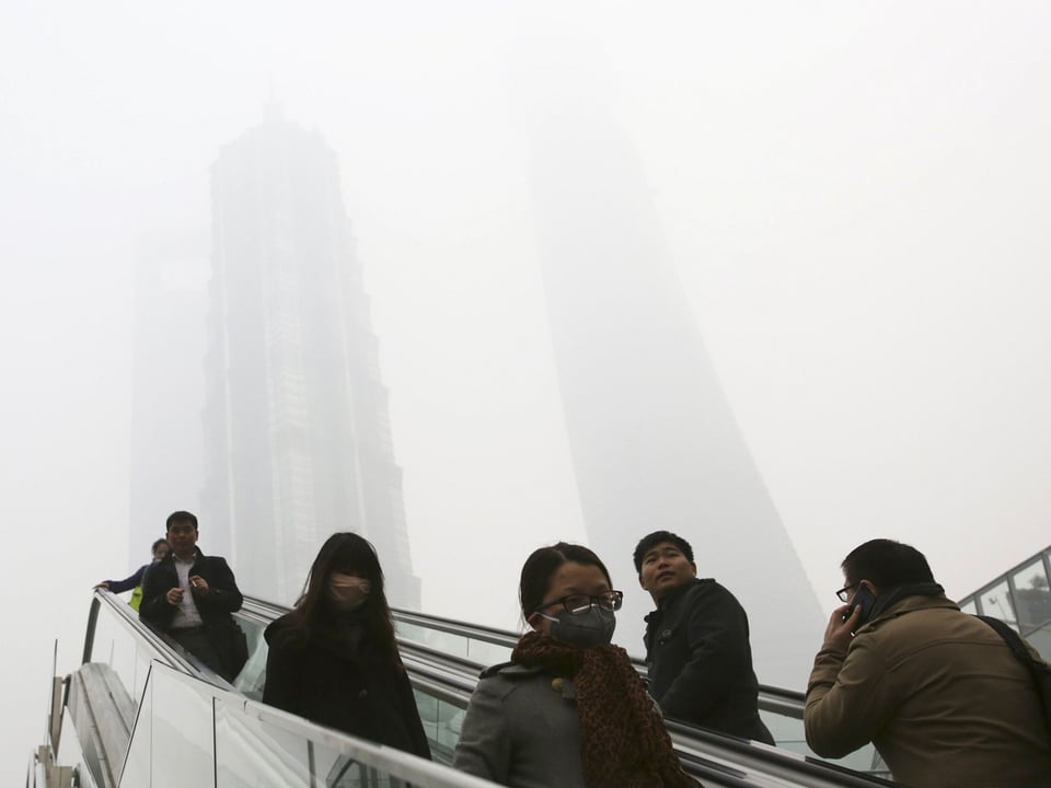Menschen auf einer Rolltreppe in Shanghai. Zu sehen ist ein dicker Nebel. 