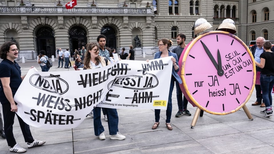 Personen demonstrieren mit einem XXL Wecker gegen das Sexualstrafrecht