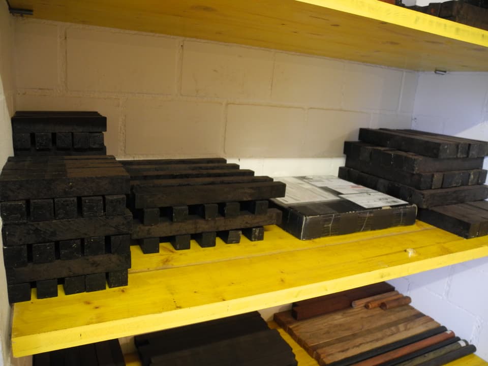 Längliche quadratische schwarze Holzstücke im Regal; Rohlinge für den Flötenbau