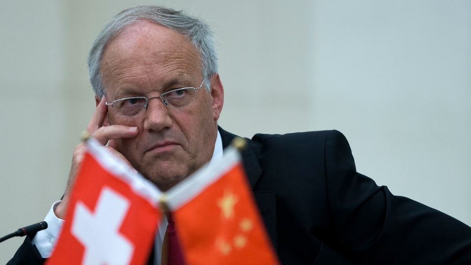 Bundesrat Johann Schneider-Ammann in Gedanken versunken hinter einem Schweizer und einem chinesischen Fähnchen.