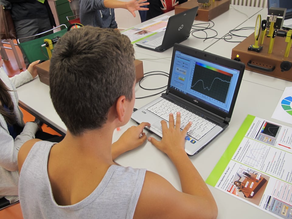 Schüler sitzt vor einem Laptop und sieht sich die Farbkurve des Spektrometers an.