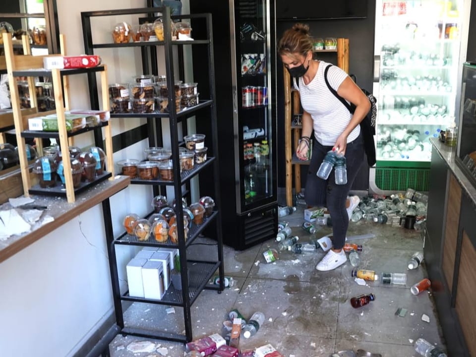 Eine Frau räumt ihr Ladenlokal auf.