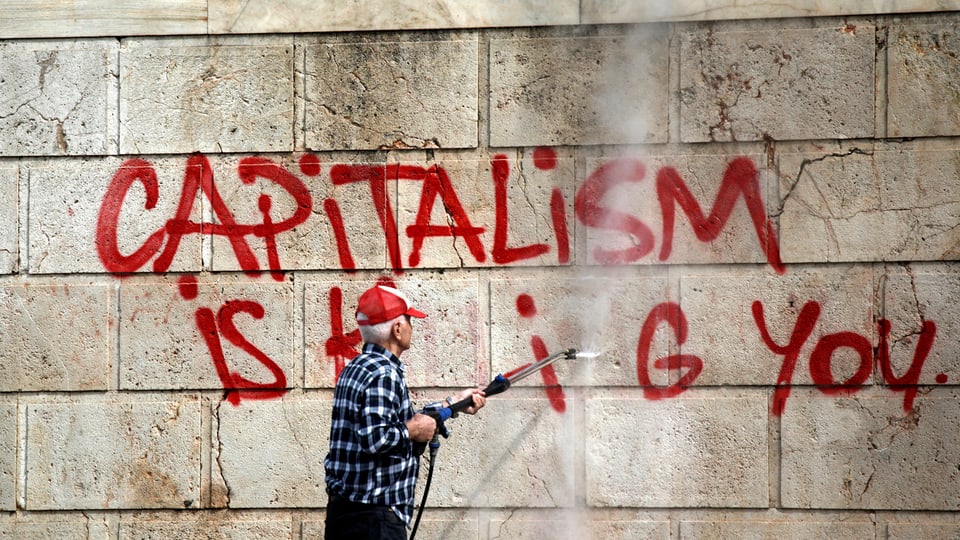 Ein Arbeiter entfernt die Graffitti-Aufschrift «Capitalism is killing you» von einer Mauer in Athen.