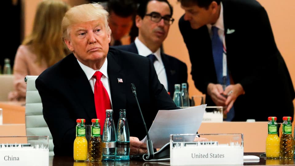 Donald Trump sitzt an einem Tisch. Vor ihm ein Schild mit der Aufschrift «United States».