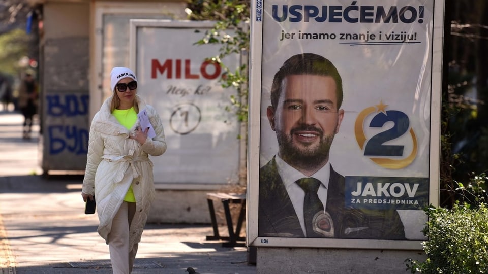 Eine Frau läuft an Wahlplakaten der beiden Kandidaten vorbei.
