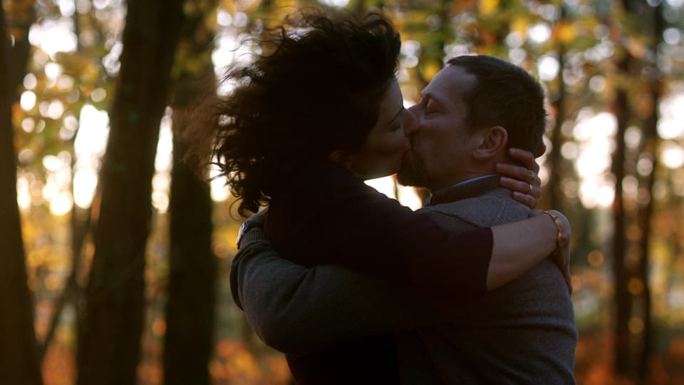 Ein Mann und eine Frau küssen sich im Wald.