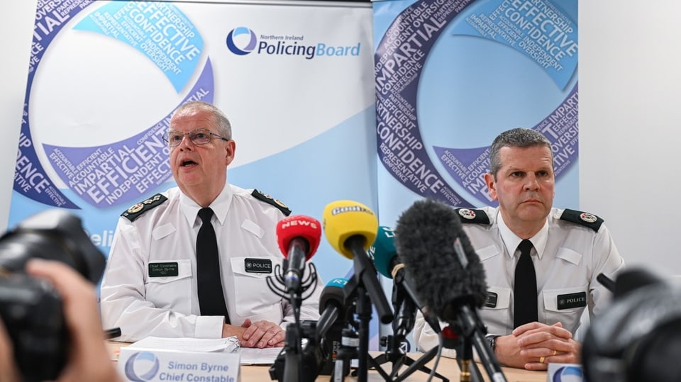 Zwei Männer in Polizeiunform vor Mikrofonen