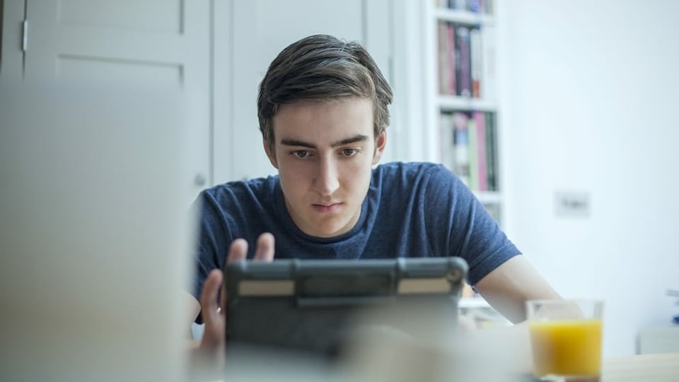 Jugendlicher schaut siuch etwas auf dem Tablet an.