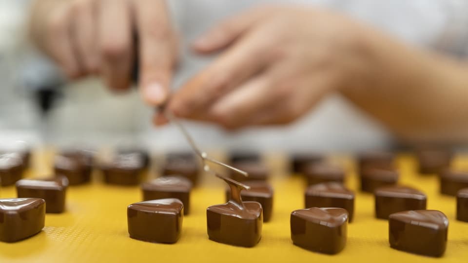 A Laderach employee uses a tool to create a triangle-shaped relief on the still-warm chocolate.