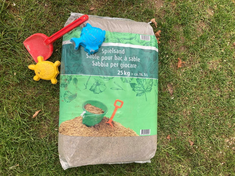 Sandsack mit 25 kg Spielsand auf Rasen mit Spielsachen
