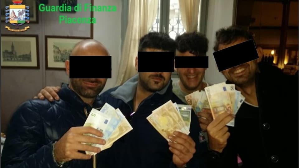 Bild, das vier der Beschuldigten mit Euro-Scheinen zeigt