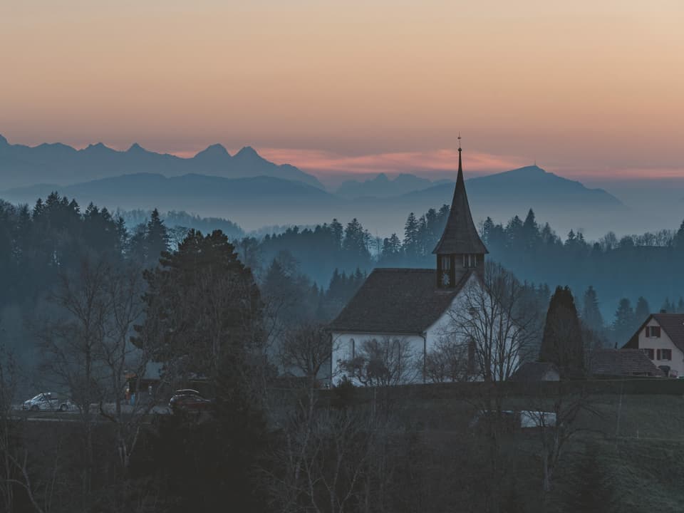 Blick auf die Kirche von Sternenberg und die Berge der Zentralschweiz, im Abendrot.