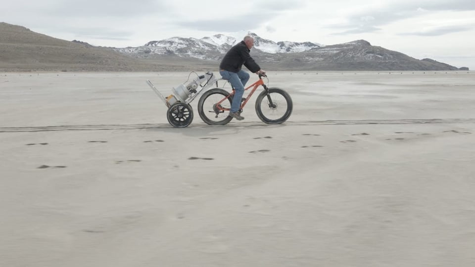 Mann zieht mit Flat-tire-Bike ein Messgerät über langen Strand