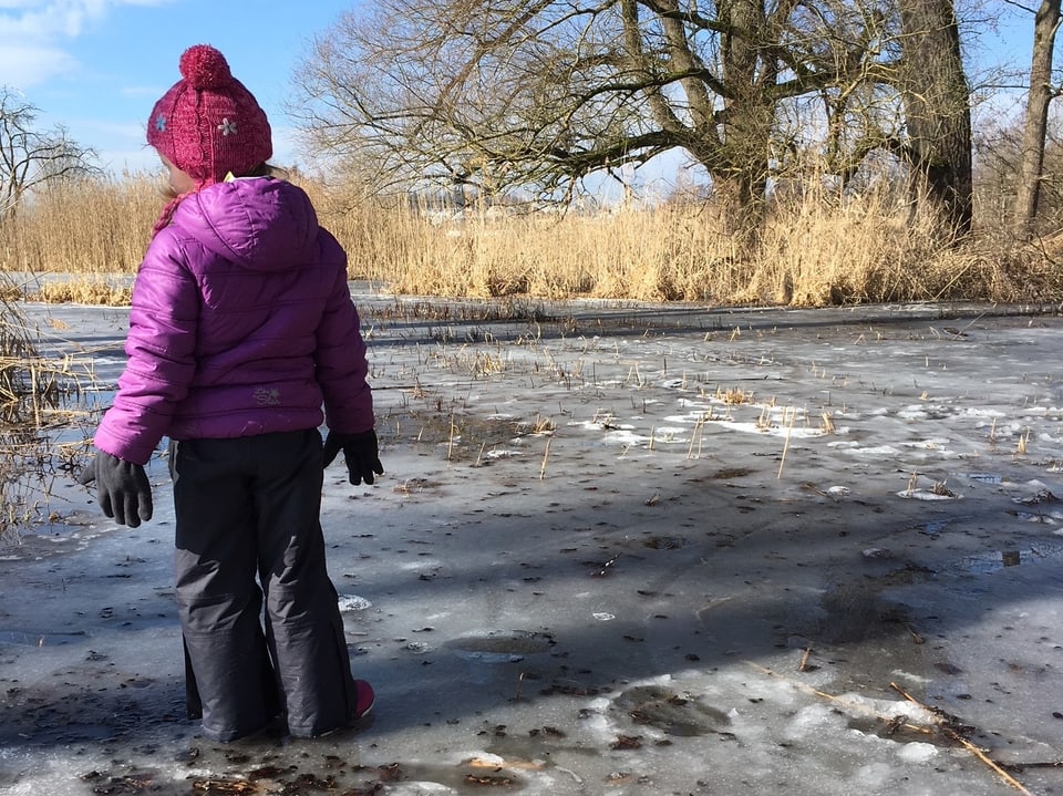 Mädchen steht auf einer gefrorenen Fläche im Moosgebiet.