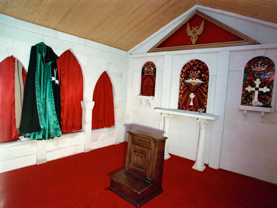 Raum, in dem Mäntel der Sonnentempler und religiöse Bilder hängen. In der Mitte steht eine Art Altar.