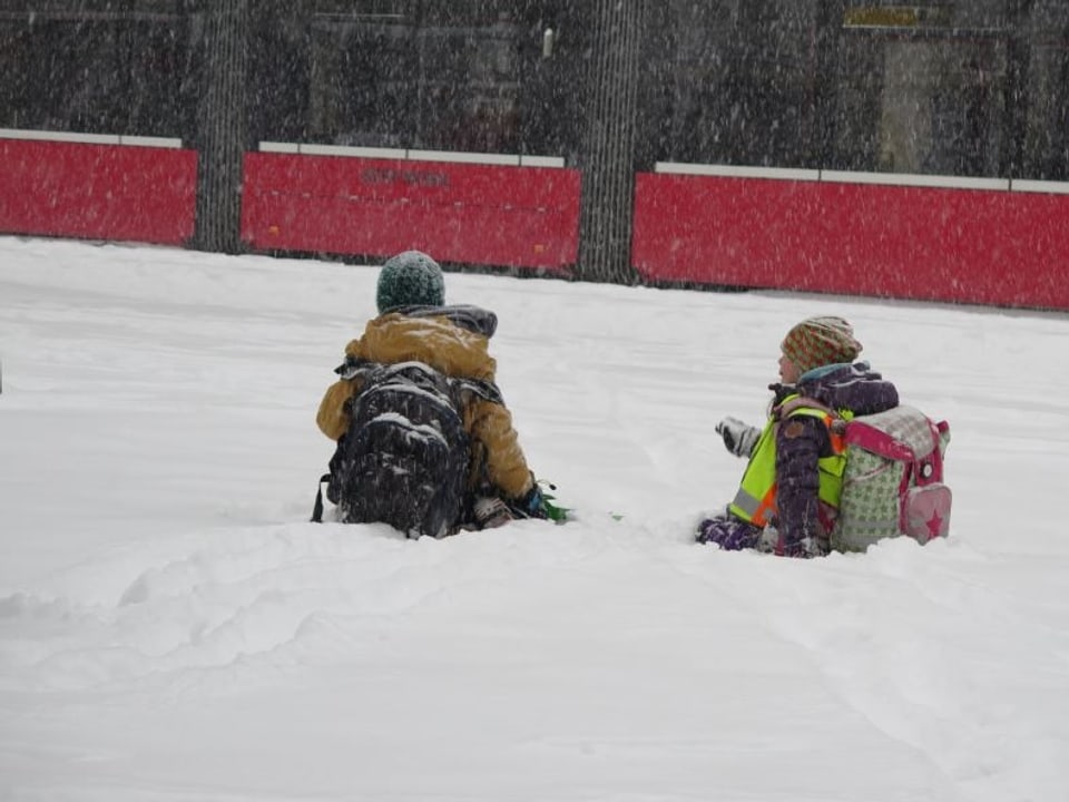 Kinder im Schnee vor einem Tram.