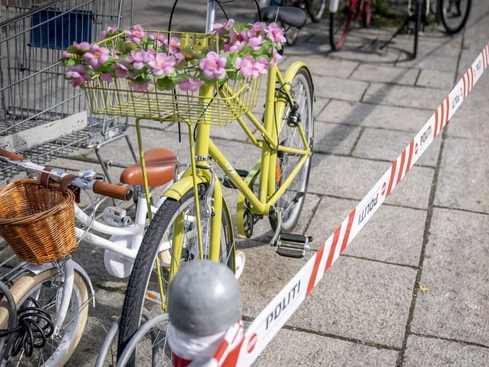 Ein gelbes mit Blumen dekoriertes Velo steht direkt hinter dem Absperrband.