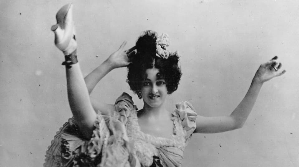 Eine Cancan-Tänzerin hebt ihr Bein hoch.