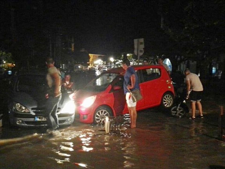 Zwei Autos auf einer überfluteten Strasse.