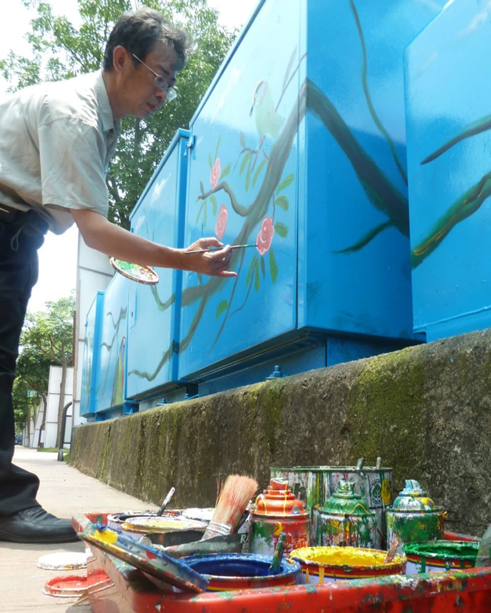 Ein taiwanesischer Maler bei der Arbeit an einem Stromkasten.