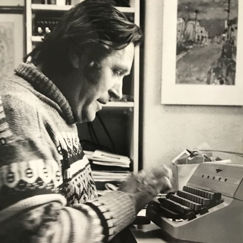 Schwarz-Weiss-Fotografie: Mann in Norweger-Pullover an Schreibmaschine.