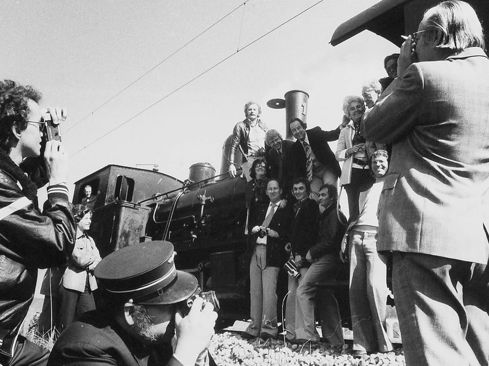 Eine Gruppe von Frauen und Männern vor einer alten Lokomotive.