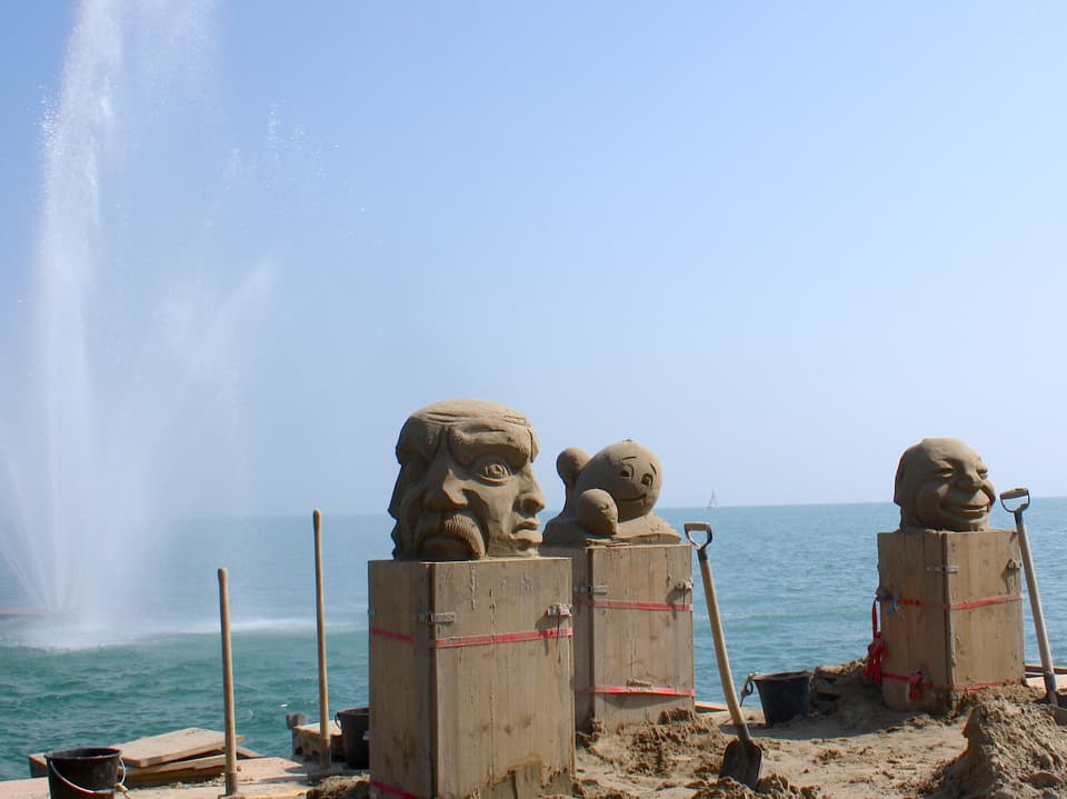 Ein paar Sandskulpturen vor dem Hintergrund des Bodensees und einem Springbrunnen.