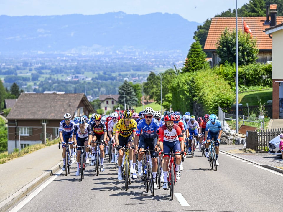 Radfahrer fahren durch eine Schweizer Gemeinde.