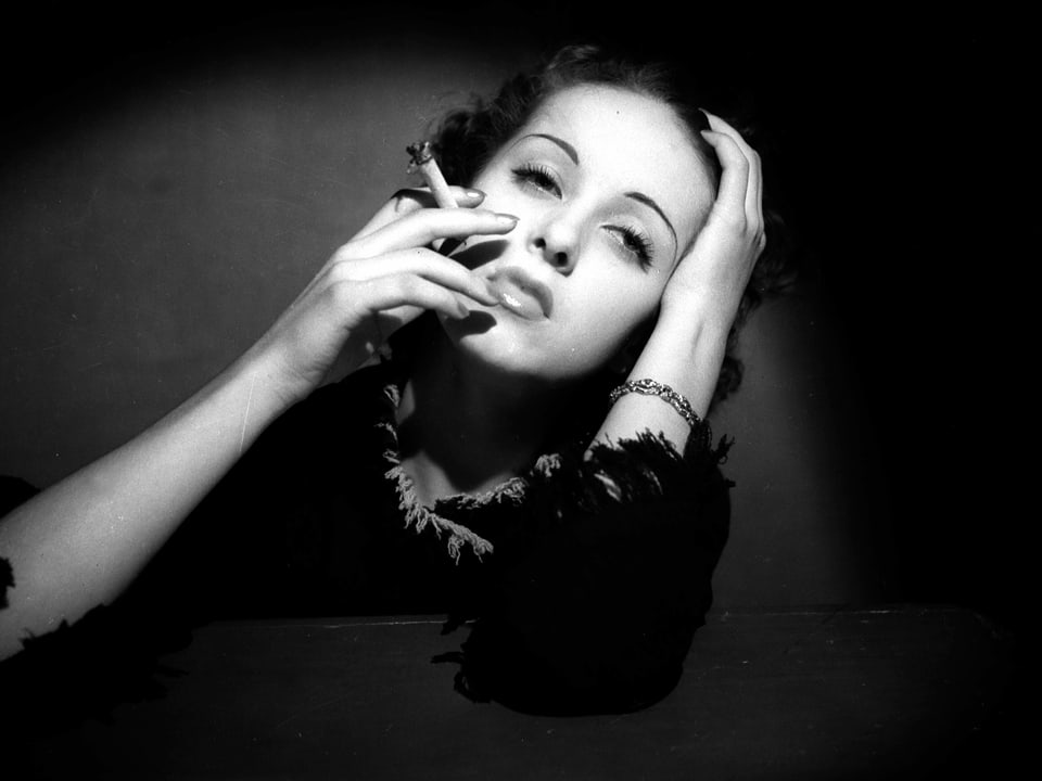 Danielle Darrieux um 1935, rauchend, mit Zigarette in der Hand.